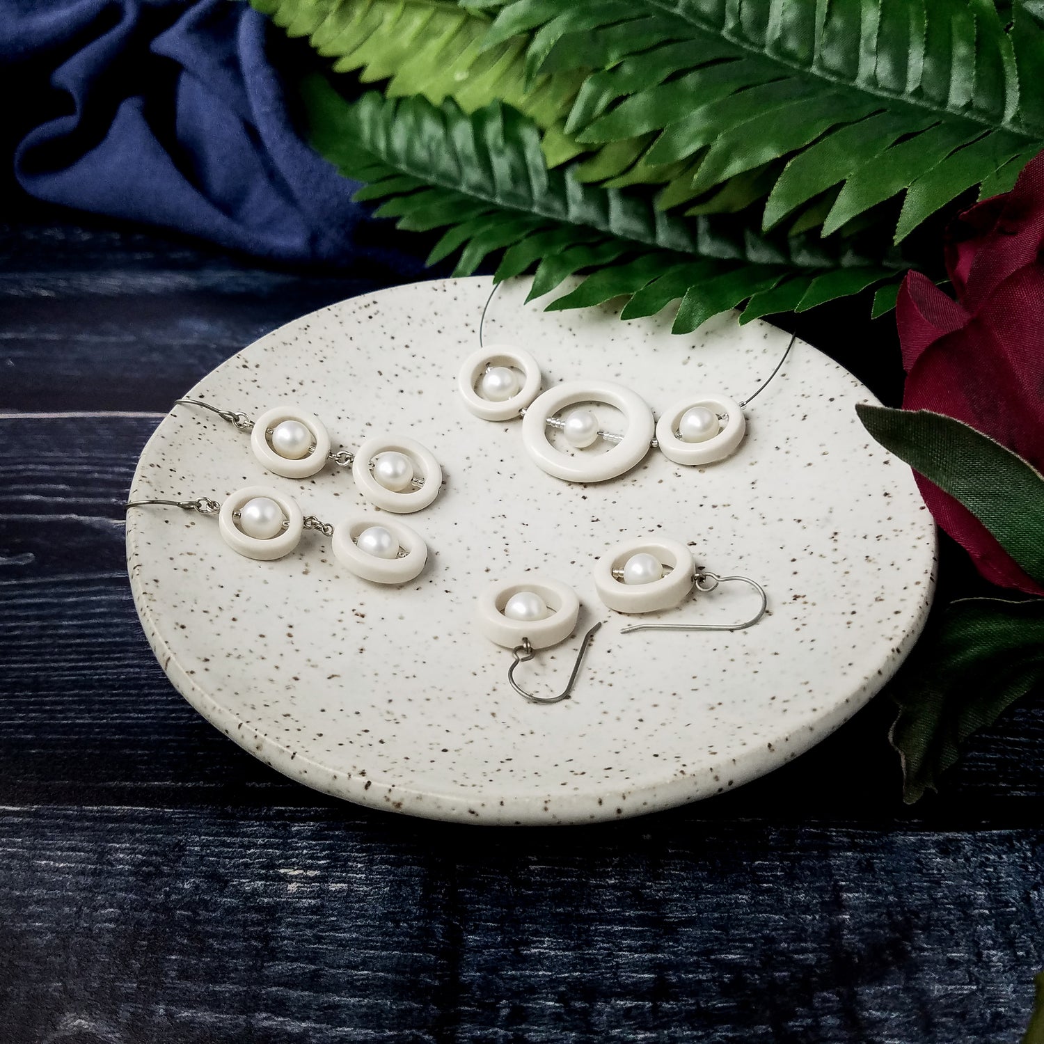 White Porcelain and Pearls Collection pieces sit in a dish with greenery behind.